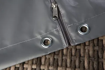Graue PROsista-Haube mit Reißverschluss und Ösen auf einem Rattanmöbel